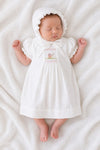 Carriage Boutique white smocked heirloom dress and ruffled bonnet set on a sleeping baby with pram embroidery.