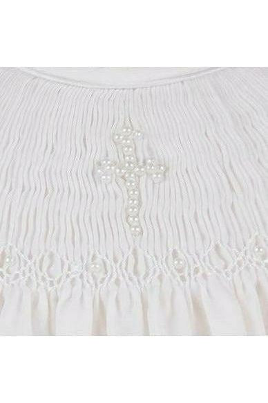 Carriage Boutique white cotton baby dress featuring intricate hand smocking and a delicate pearl cross detail.