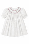 Carriage Boutique baby girl dress in off-white with black polka dots, smocked yoke, and floral embroidery.