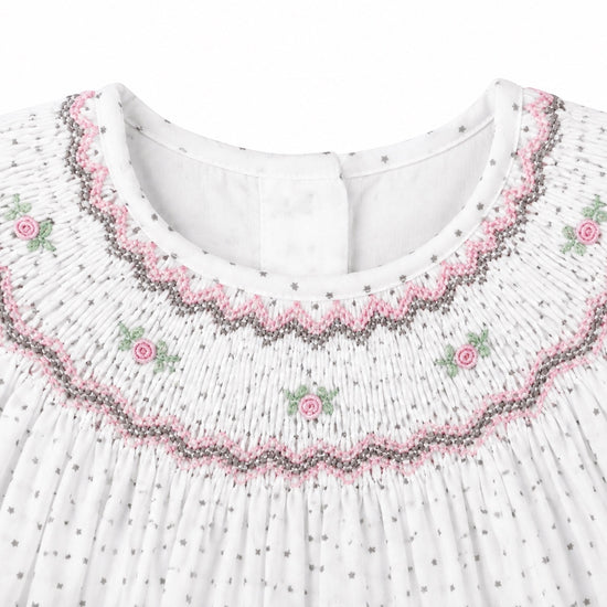 Carriage Boutique off-white baby dress with smocked yoke, pink and green floral embroidery, and tiny black star print.