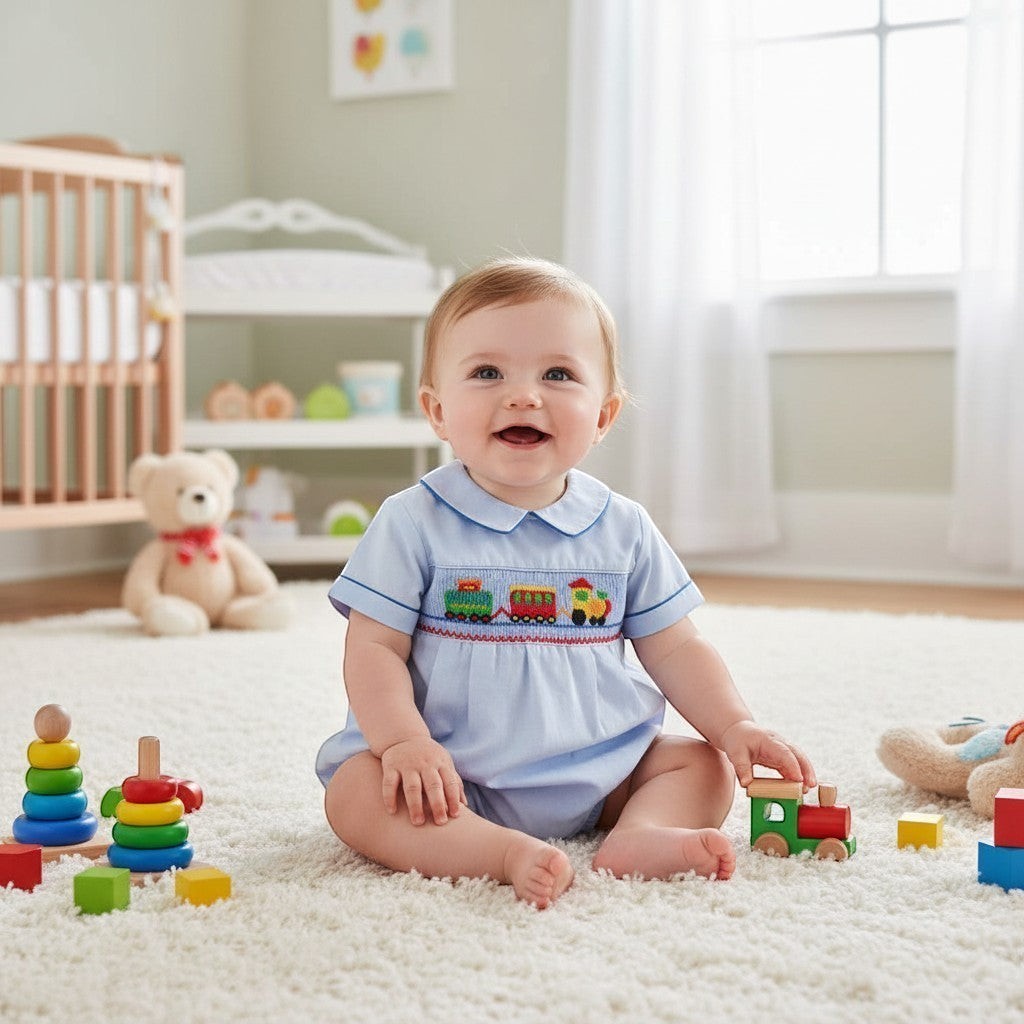 Carriage Boutique light blue smocked bubble romper with train motif and Peter Pan collar