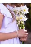 Carriage Boutique sterling silver cross bracelet with freshwater pearls and crystals worn by a girl holding daisies.