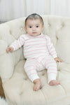 Baby wearing a Carriage Boutique white and blush pink striped cotton long-sleeve legging set while sitting on a chair.