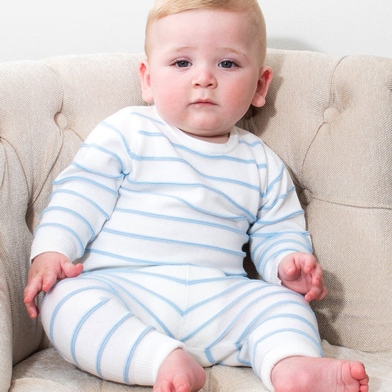 Baby wearing a Carriage Boutique white and sky-blue striped long-sleeve top and legging set while sitting in a chair.