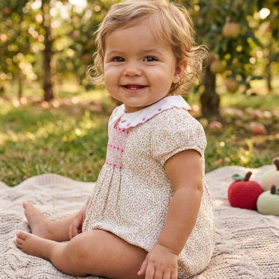 Carriage Boutique baby girl bubble romper in tan floral print with puff sleeves and pink smocked diamond detailing.