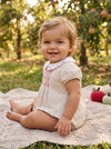 Carriage Boutique baby girl bubble romper in tan floral print with puff sleeves and pink smocked diamond detailing.