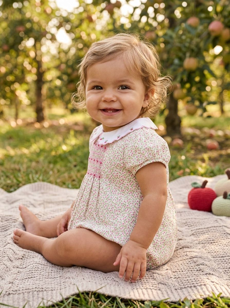 Carriage Boutique baby girl bubble romper in tan floral print with puff sleeves and pink smocked diamond detailing.