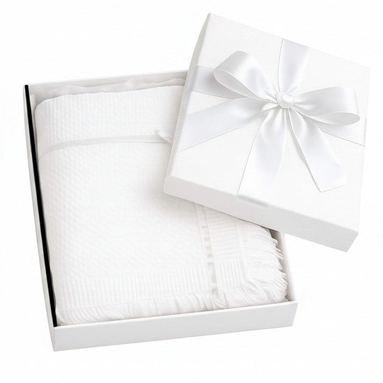 Carriage Boutique white baby blanket with lace trim and cross detail, presented in a gift box with a satin ribbon.