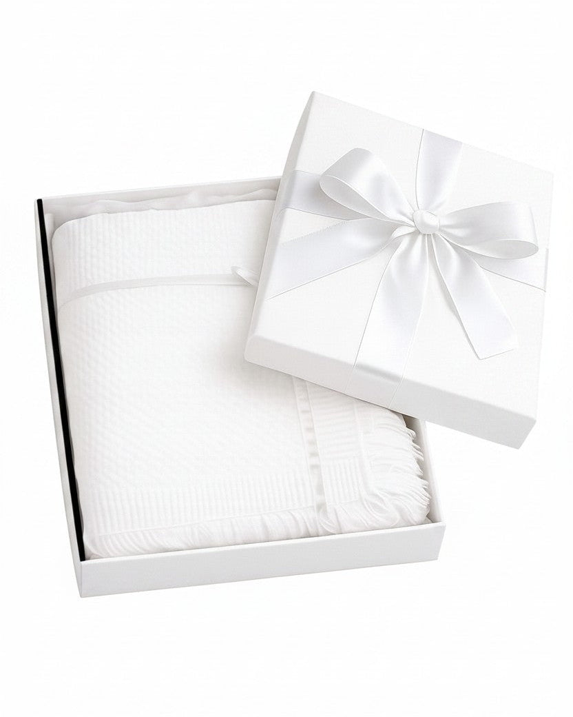 Carriage Boutique white baby blanket with lace trim and cross detail, presented in a gift box with a satin ribbon.
