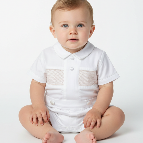 Carriage Boutique white baby boy bobby suit with hand smocked detailing, Peter Pan collar, and satin buttons.