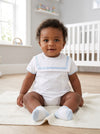 Carriage Boutique baby boy wearing a white bubble romper with blue trim, Peter Pan collar, and matching blue socks.