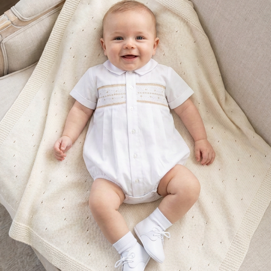 Carriage Boutique white baby boy christening bubble with smocked embroidery and Peter Pan collar on a cream blanket