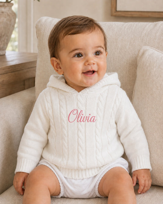 Carriage Boutique white cotton cable knit hooded baby sweater with personalized pink embroidery on the chest.