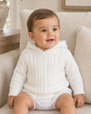 Carriage Boutique white cable knit hooded baby sweater made of soft cotton worn by a smiling baby