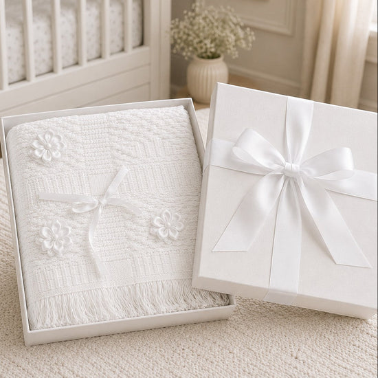 Carriage Boutique Julius Berger white christening blanket with floral accents and fringe in a gift box.