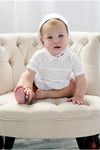 Carriage Boutique baby boy white christening bubble romper with smocked cross detail and matching bonnet on chair