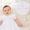 Carriage Boutique white baby christening gown with pink cross embroidery and matching bonnet on an infant