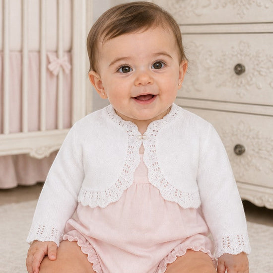 Carriage Boutique white cotton knit bolero shrug with textured pattern and single button on a baby girl
