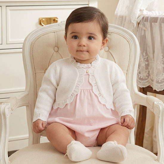 Carriage Boutique white cotton knit bolero shrug with textured pattern worn by a baby girl on a vintage chair