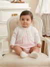 Carriage Boutique white cotton knit bolero shrug with textured pattern worn by a baby girl on a vintage chair
