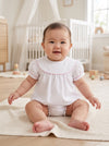 Carriage Boutique white cotton baby girl bubble romper with flutter sleeves and pink picot trim in a nursery setting