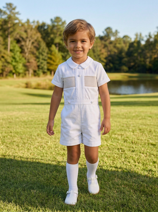 Carriage Boutique white cotton bobby suit with hand smocked detail, Peter Pan collar, and satin buttons on a young boy