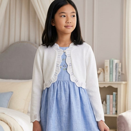 Carriage Boutique white cotton bolero shrug with textured knit pattern and single button closure worn by a young girl