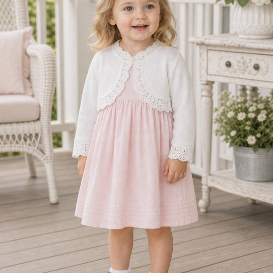Carriage Boutique white cotton bolero shrug with textured knit pattern worn by a toddler girl over a pink dress