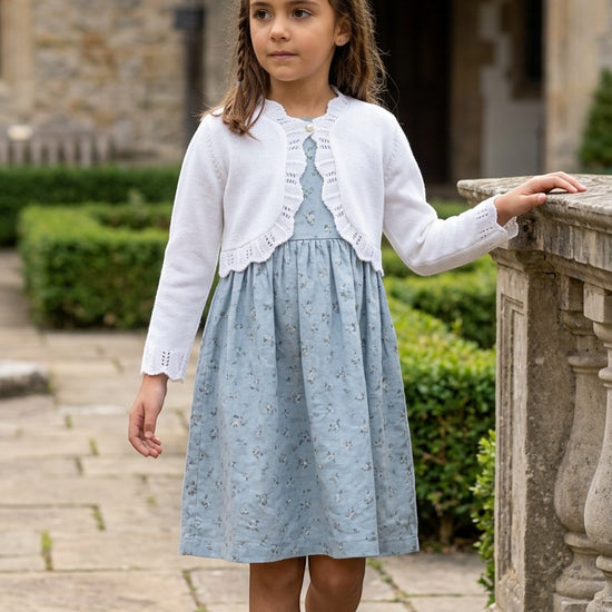 Carriage Boutique white cotton knit bolero shrug with textured pattern worn by a girl over a blue floral dress