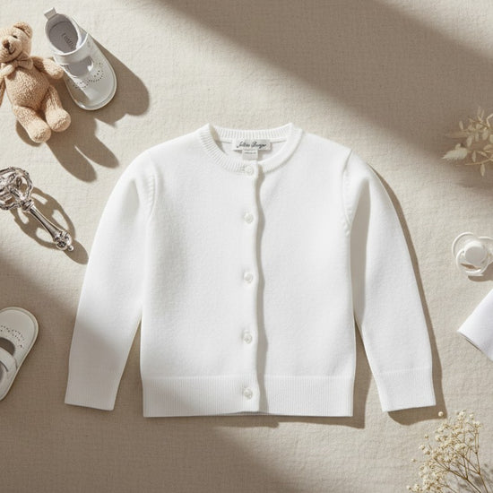 Carriage Boutique white cotton cashmere baby girl cardigan with button front and ribbed trim on a neutral background