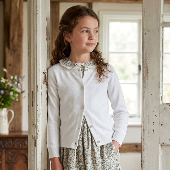 Carriage Boutique white cotton cashmere cardigan worn by a young girl with a floral dress and lace collar