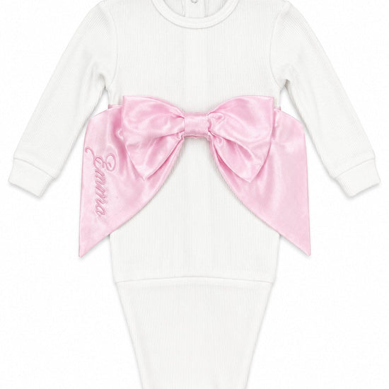 Carriage Boutique newborn white ribbed cotton swaddle bag featuring a large pink satin bow and personalized embroidery