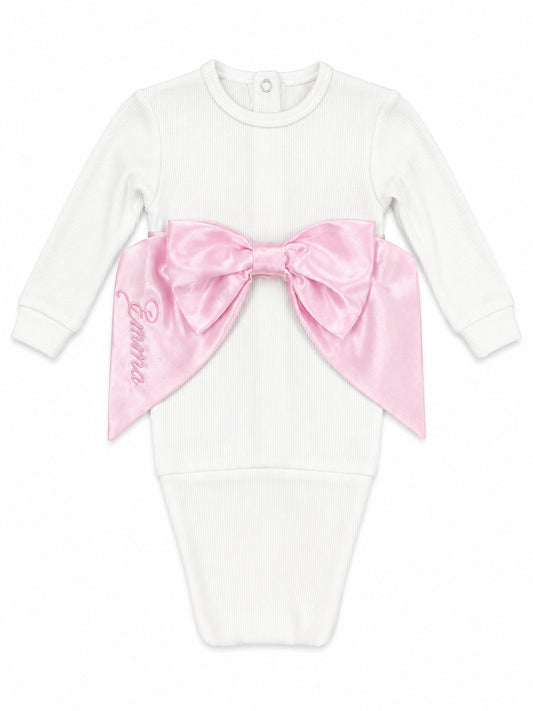 Carriage Boutique white cotton newborn swaddle bag featuring a large pink satin bow and personalized embroidery.