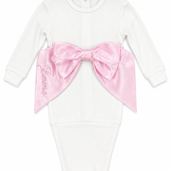 Carriage Boutique white cotton newborn swaddle bag featuring a large pink satin bow and personalized embroidery