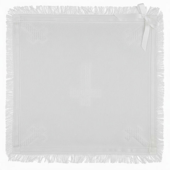 Carriage Boutique white baby blanket featuring a cross pattern, delicate fringe trim, and a decorative ribbon bow.
