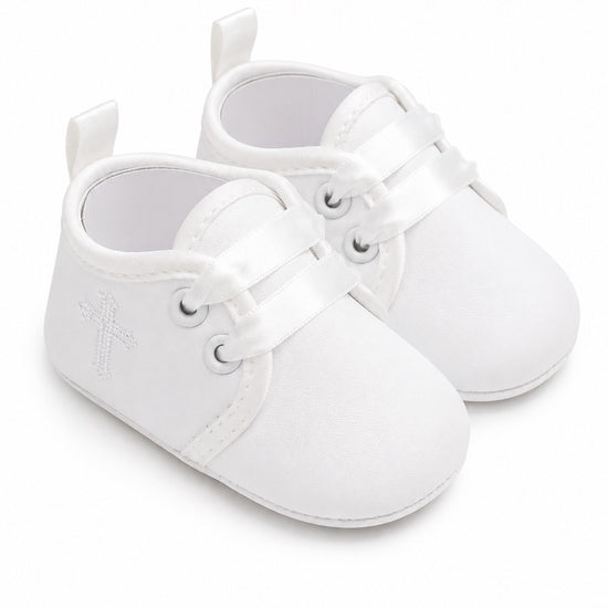 Carriage Boutique white baby christening shoes with satin ribbon laces and a delicate embroidered cross detail.