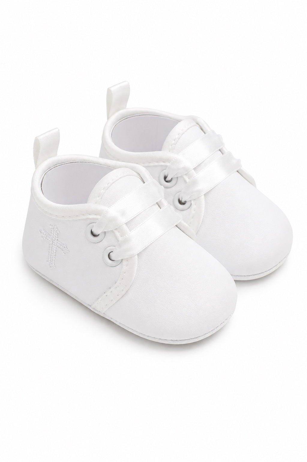 Carriage Boutique white baby christening shoes with satin ribbon laces and a delicate embroidered cross detail.