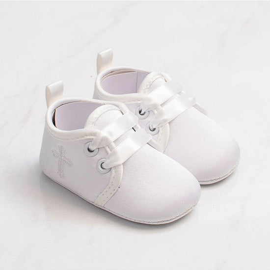 Carriage Boutique white baby christening shoes featuring a delicate embroidered cross and satin ribbon laces.