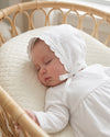 Carriage Boutique white cotton christening bonnet with embroidered cross, scalloped edge, and satin ribbon tie on baby