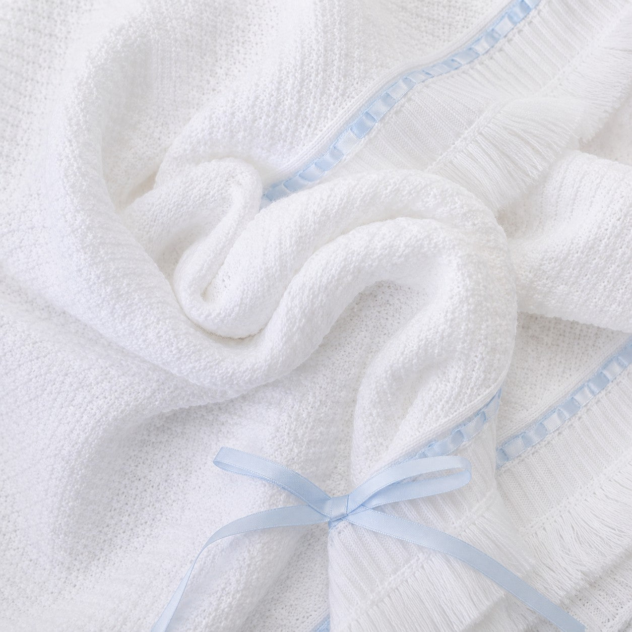 Carriage Boutique white knit baby blanket with blue satin ribbon trim and a delicate bow accent