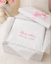 Carriage Boutique white knit baby blanket with pink personalized embroidery and fringe in a gift box with pink ribbon.
