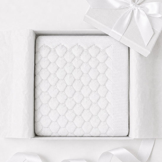 Carriage Boutique white cotton knit baby blanket with shell texture in a gift box with a satin ribbon.
