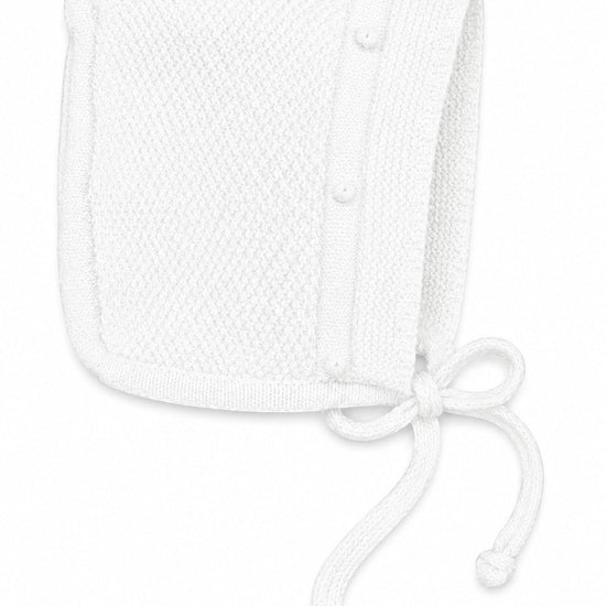Carriage Boutique white knit baby bonnet with textured pattern and delicate tie closure for a special occasion.