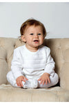 Carriage Boutique white knit 3-piece baby bris outfit with matching bonnet worn by a smiling baby in a chair