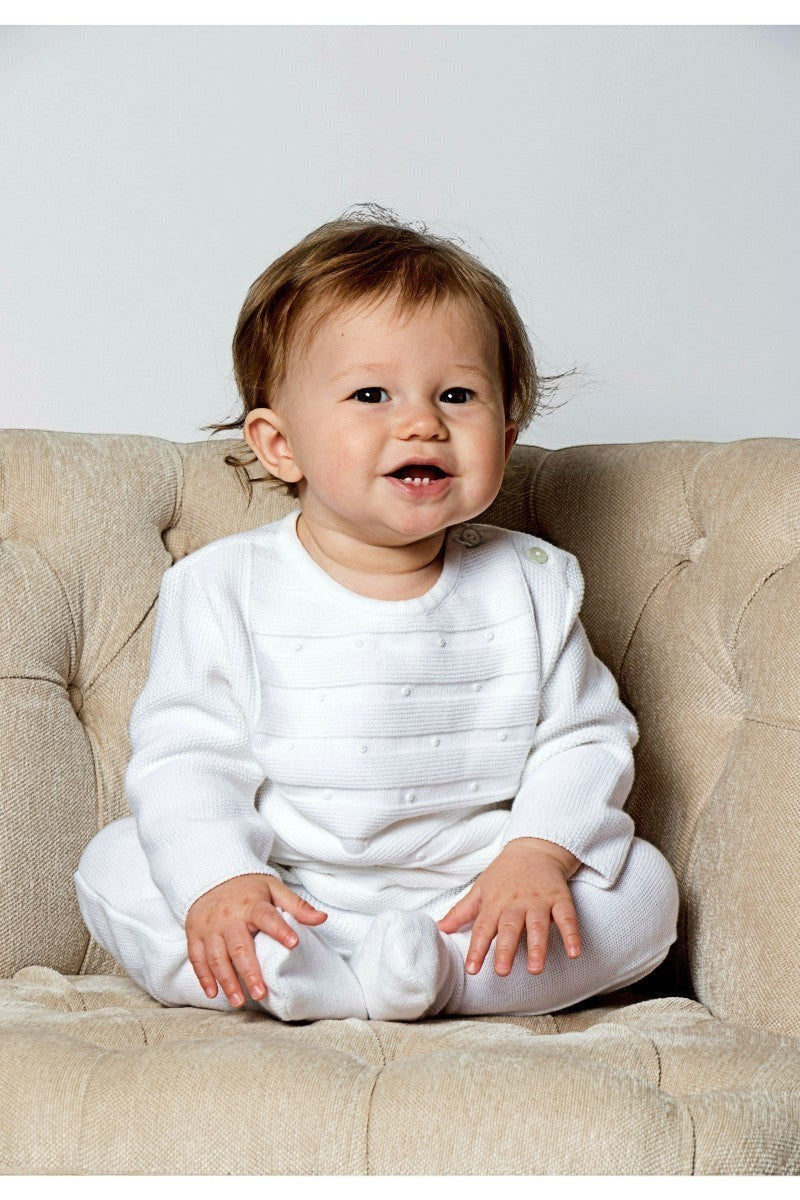 Carriage Boutique white knit 3-piece baby bris outfit with matching bonnet worn by a smiling baby in a chair