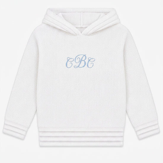 Carriage Boutique soft white knit baby hoodie with blue monogram embroidery on the chest and a zip-back closure.