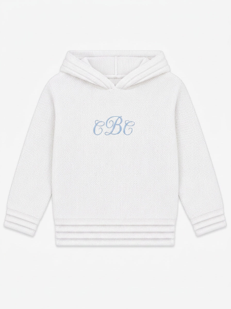 Carriage Boutique soft white knit baby hoodie with blue monogram embroidery on the chest and a zip-back closure.
