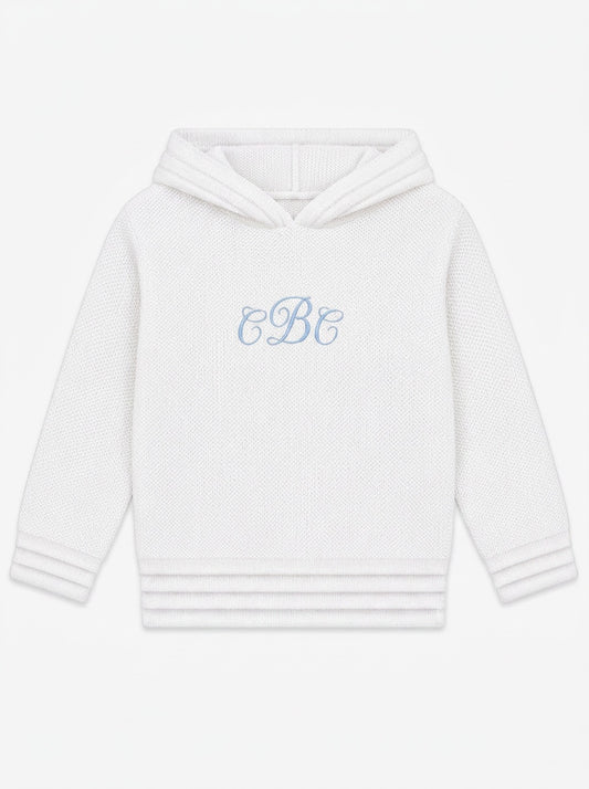 Carriage Boutique soft white knit baby hoodie with blue monogram embroidery on the chest and a zip-back closure.