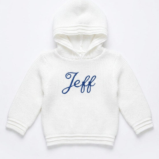 Carriage Boutique white knit baby hoodie with hood and blue embroidered name on the front