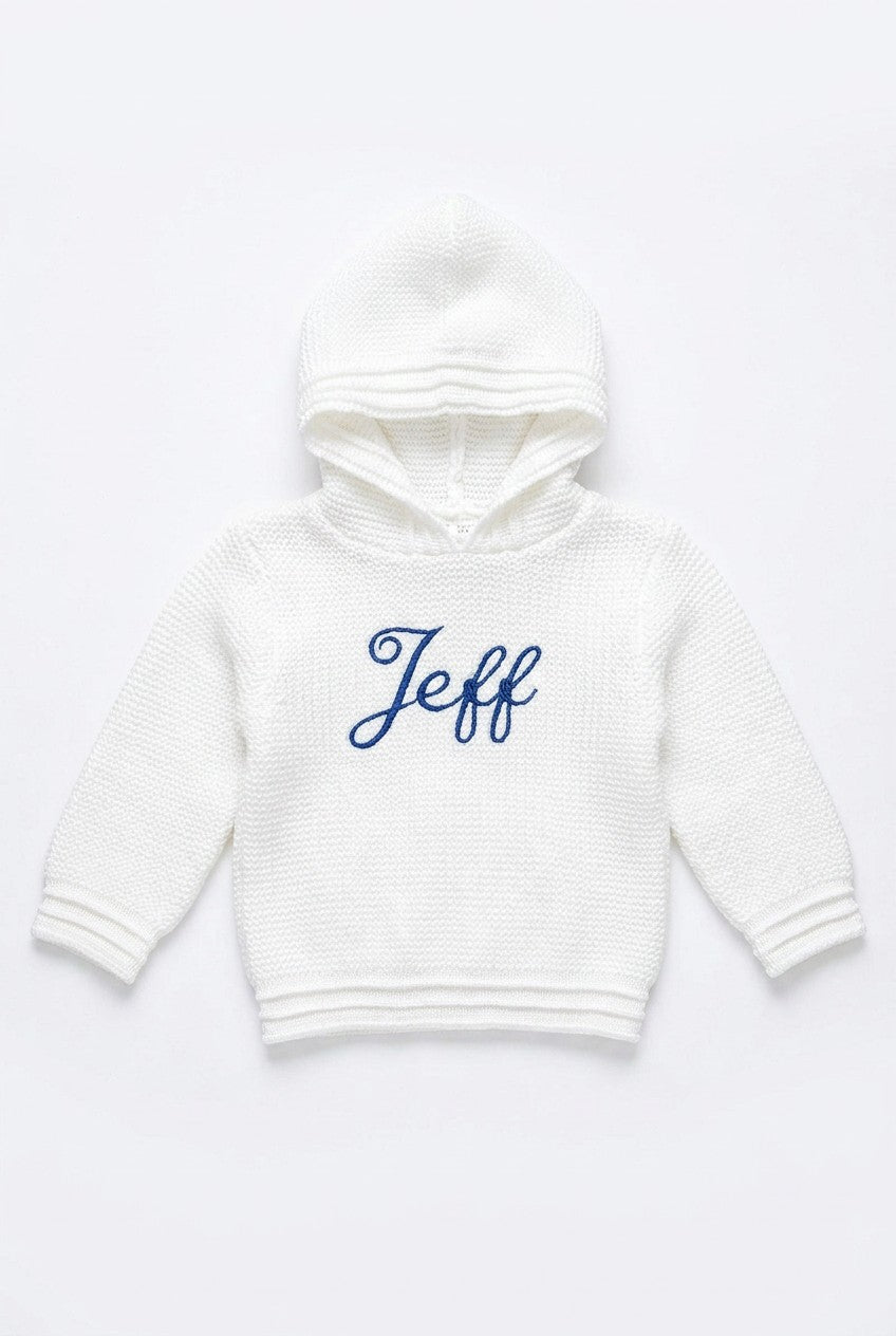 Carriage Boutique white knit baby hoodie with hood and blue embroidered name on the front